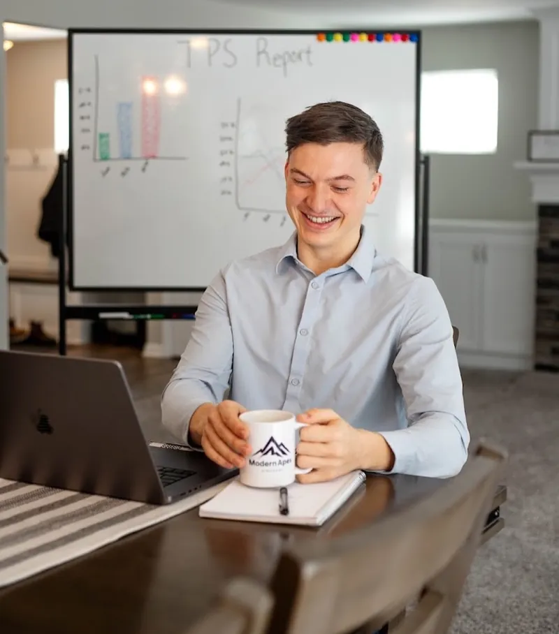 Nick Radachy, owner of Modern Apex Strategies, at his desk with a Modern Apex mug