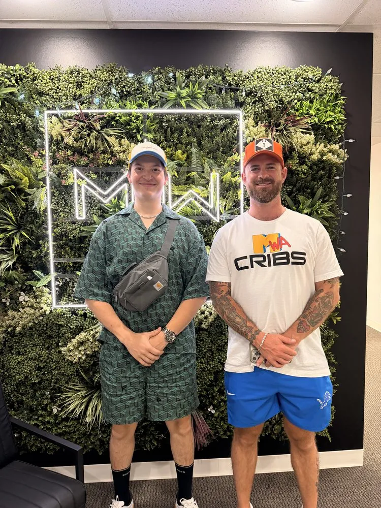 Nick Radachy with Mark Whitehead, owner of Mark White & Associates, in front of the MWA sign at their Troy office