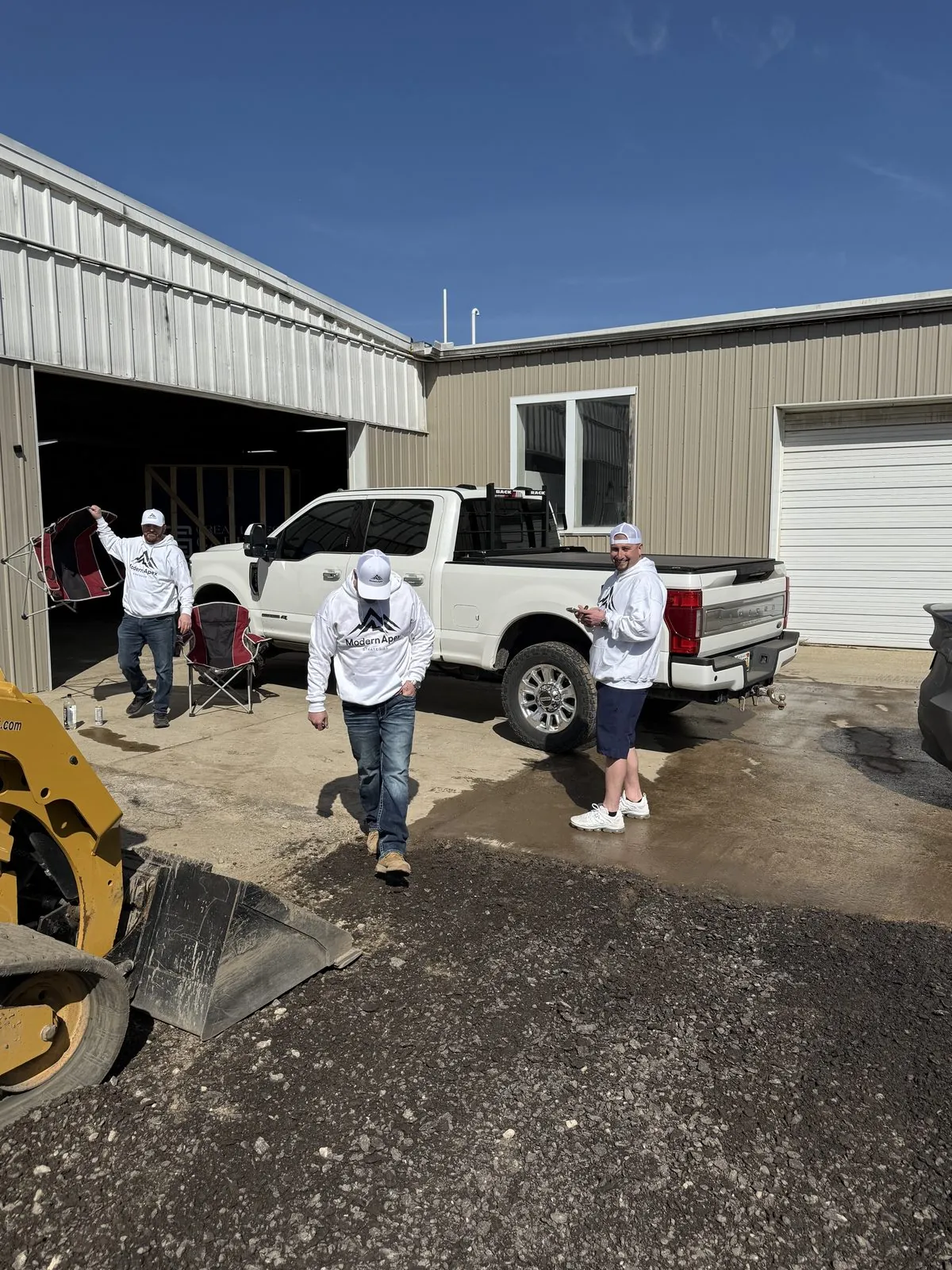 The crew on-site at a client property, Modern Apex hoodies, work truck in the background