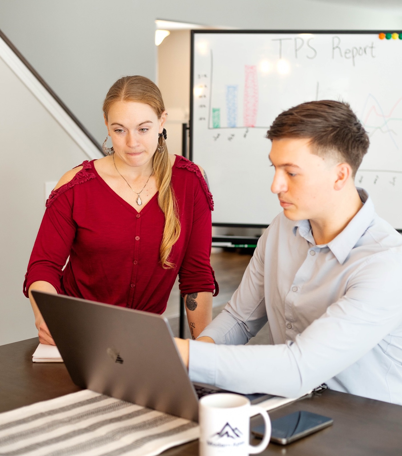 Nick and Emilia reviewing campaign data on a laptop with a Modern Apex mug on the table