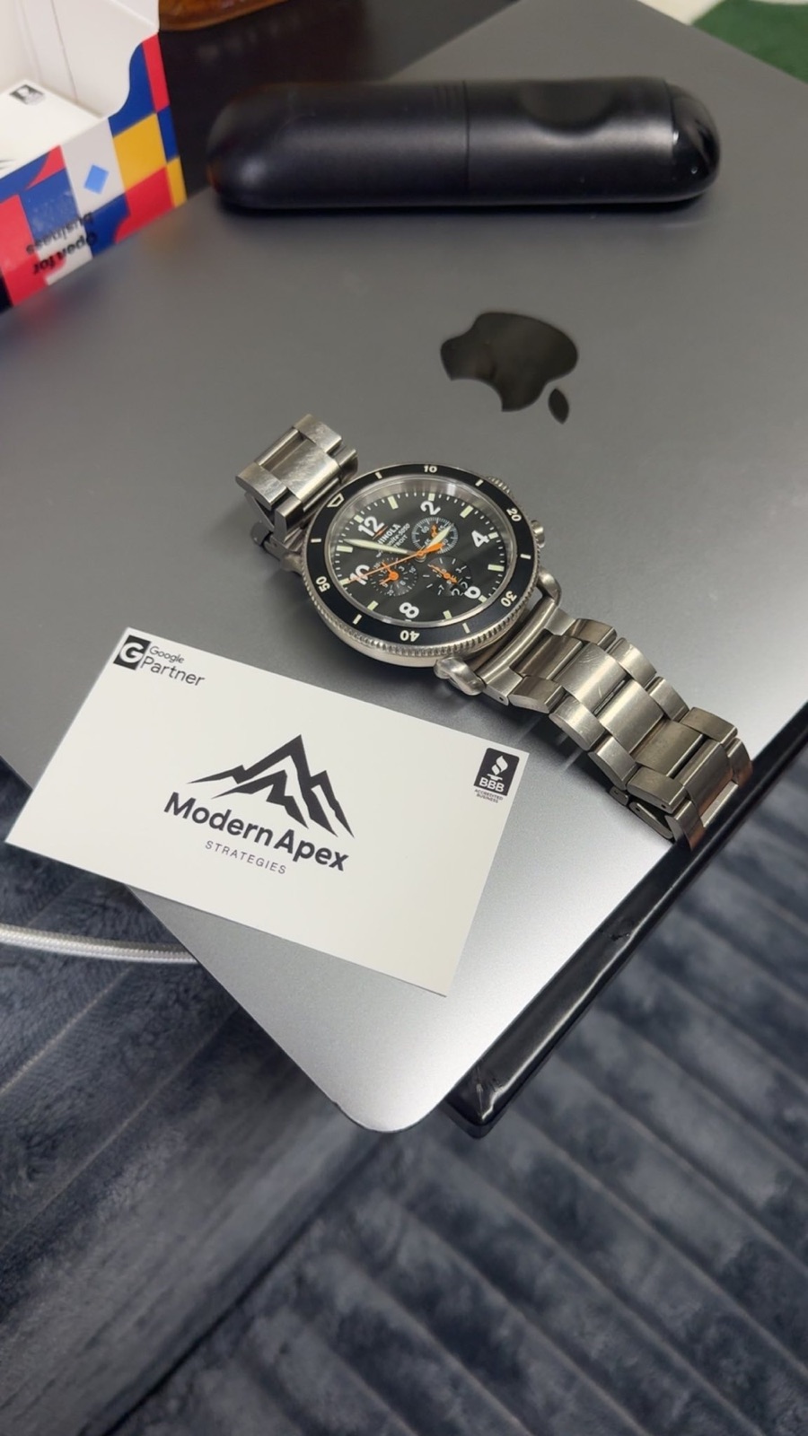Modern Apex Strategies Google Partner business card next to a watch on a MacBook